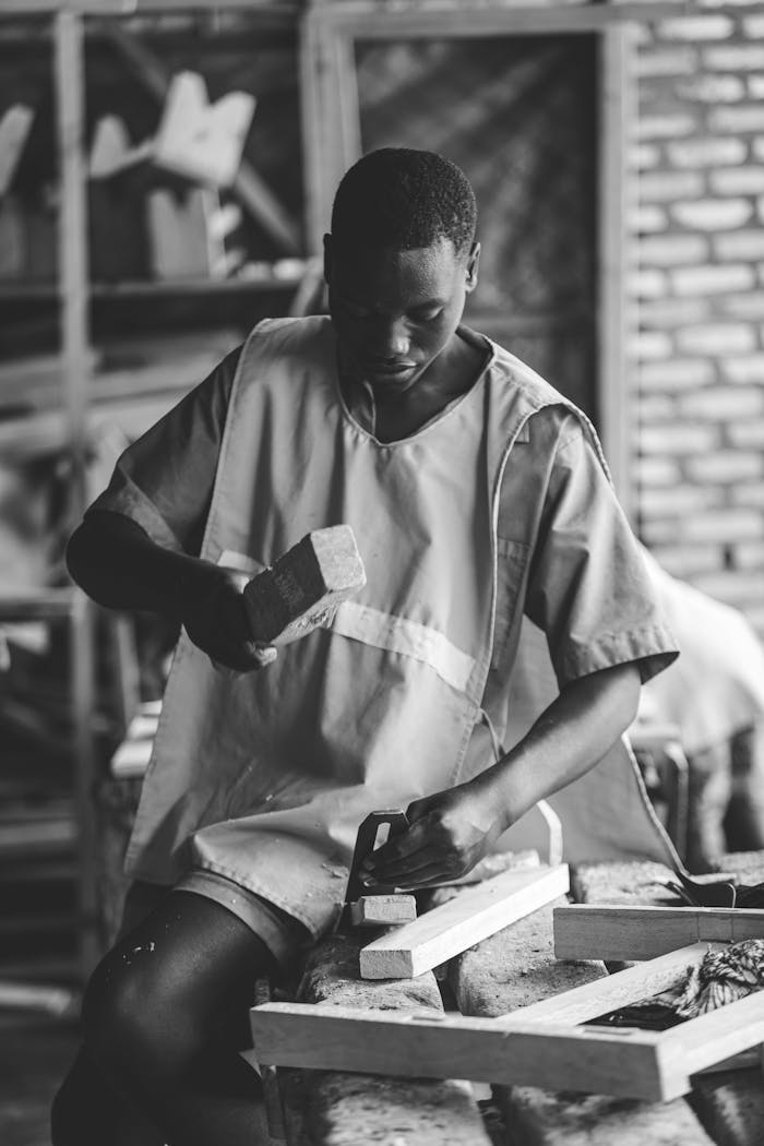 A young African American man skillfully working with wood in an indoor carpentry workshop.